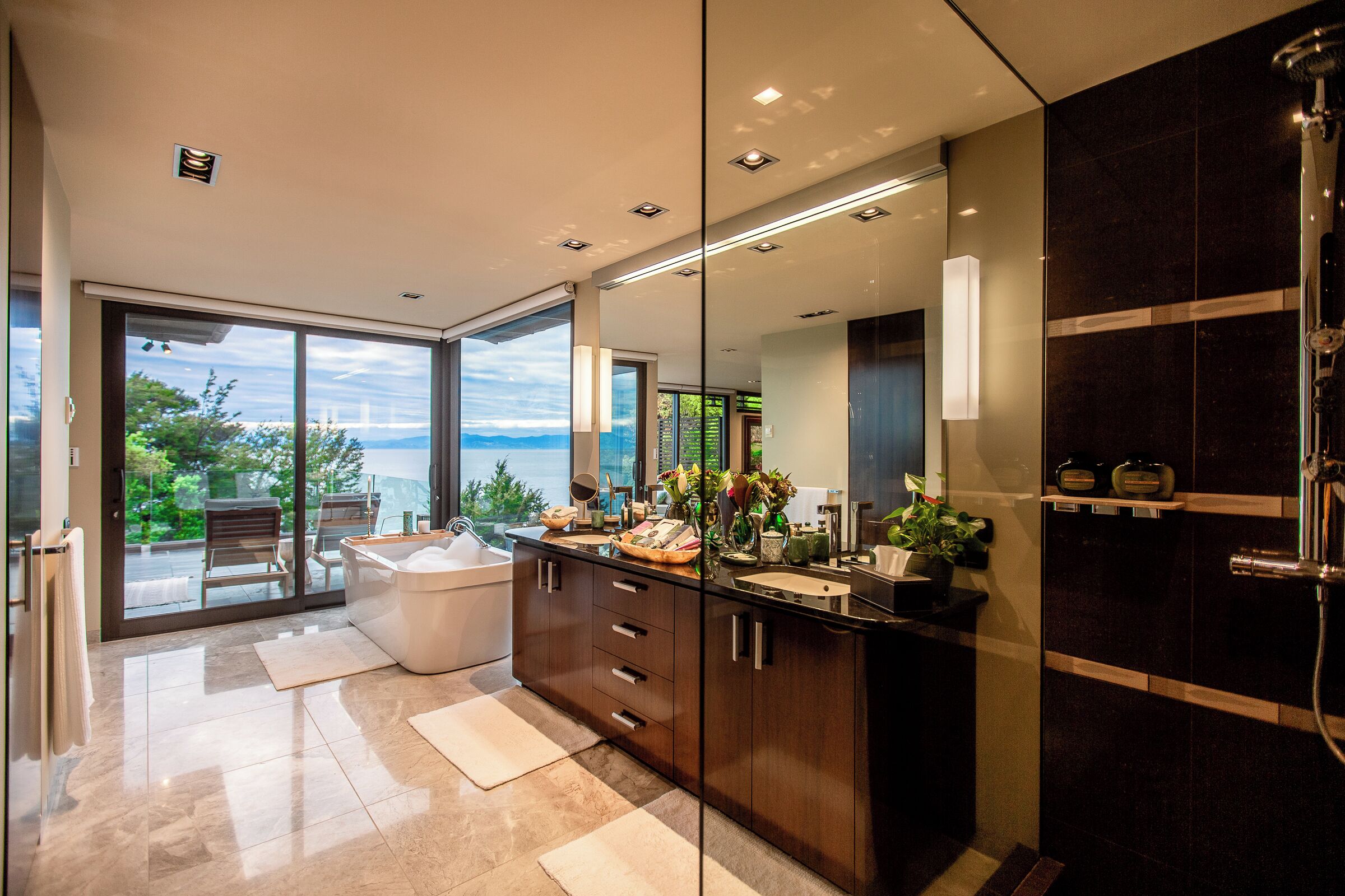 A modern bathroom with a large mirror, a bathtub, and a shower area.
