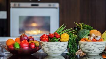 Two bowls of assorted vegetables on a kitchen counter with a stove in the background.