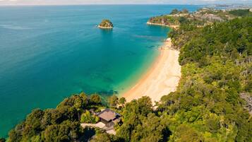 An aerial view of a coastal property with a beach, forested area, and a small island.