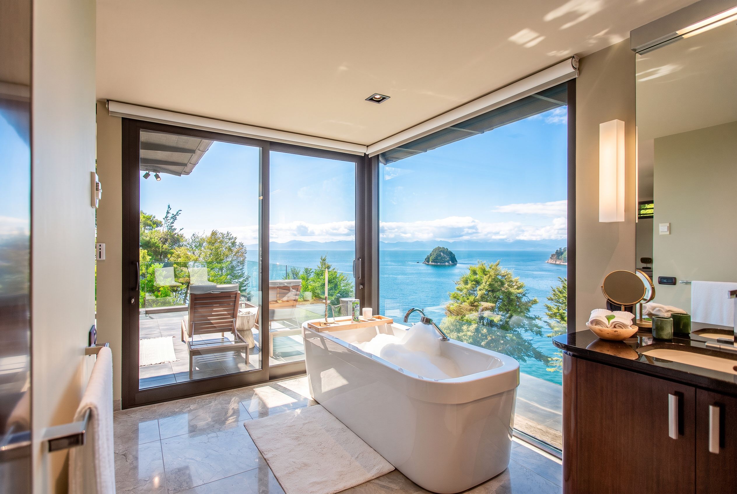 Un bagno moderno con una vasca da bagno ampia, una doccia vetrata e vista sul mare.