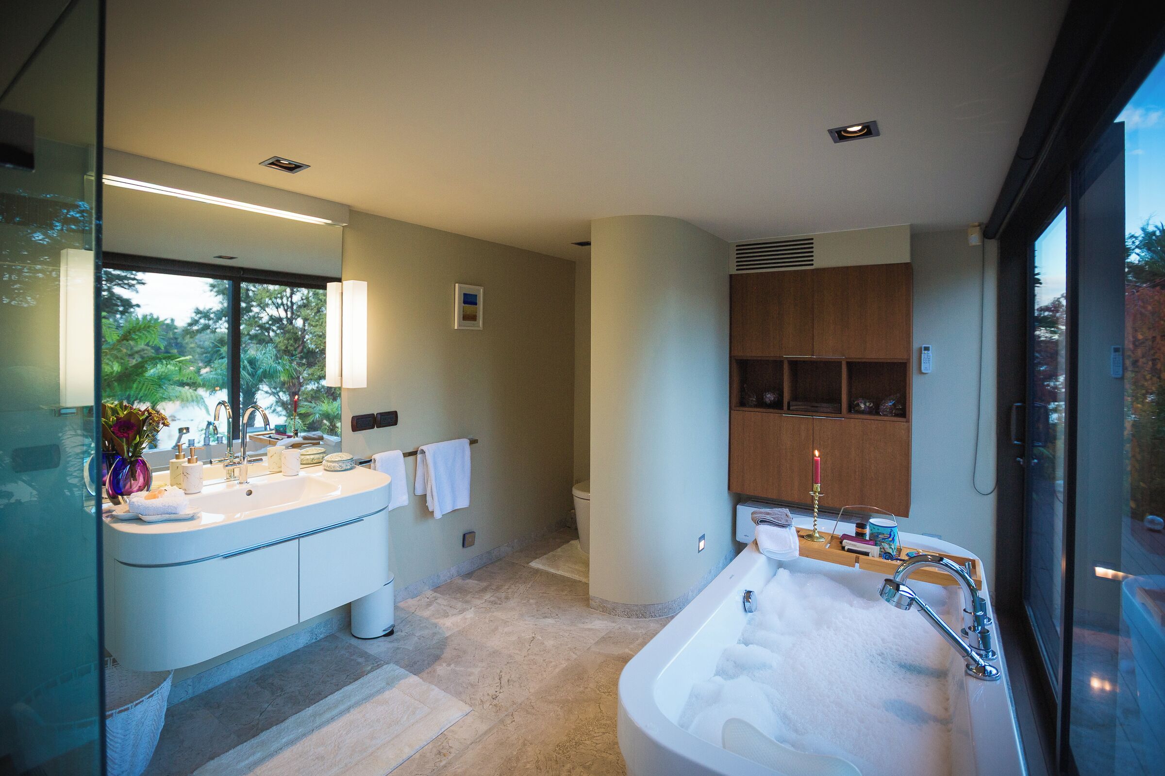 Un baño moderno con lavamanos doble, una bañera independiente y un ventanal con vistas al exterior.