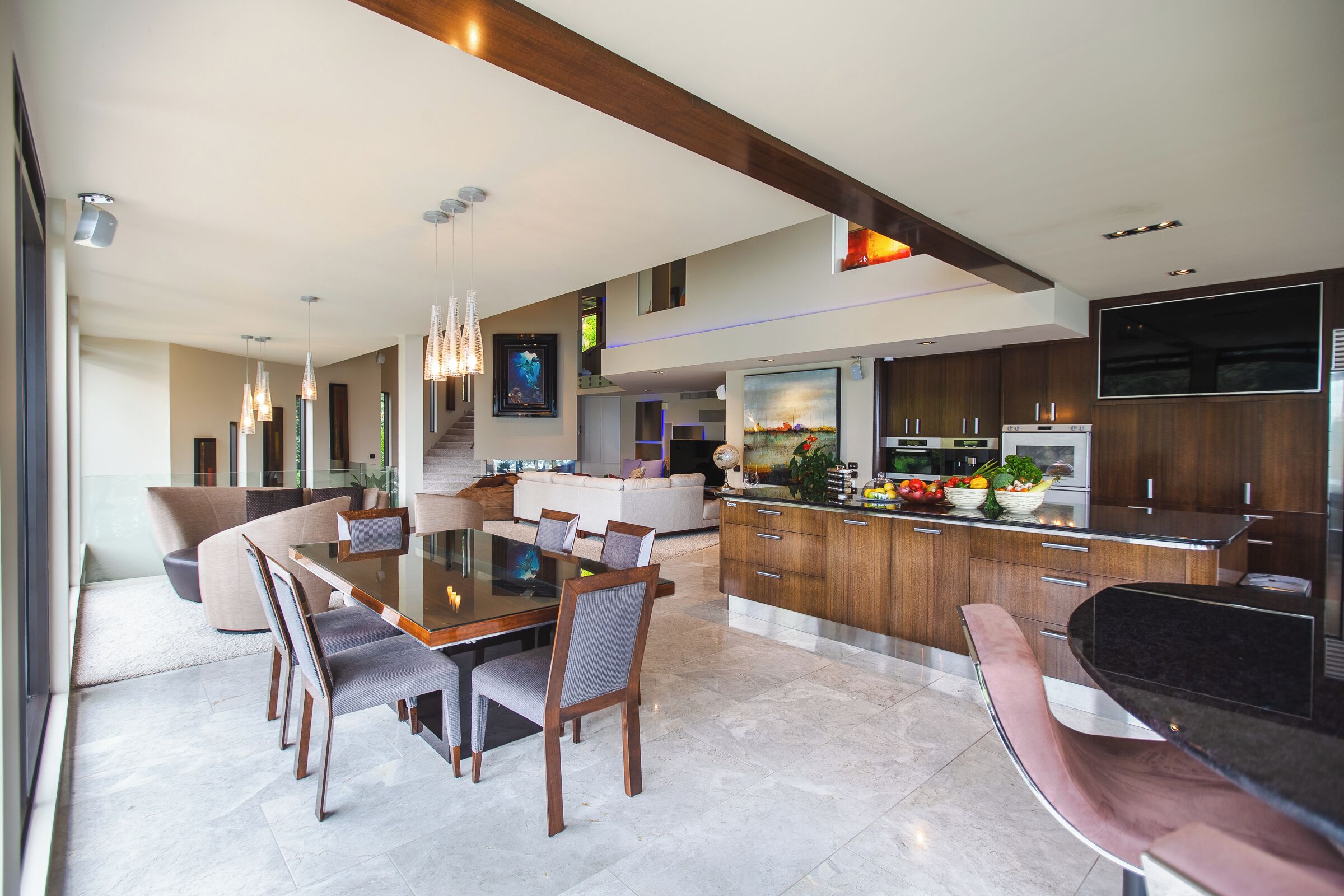 Una cocina moderna con comedor, que cuenta con una isla grande con un lavamanos, un televisor de pantalla plana montado sobre la isla y varios electrodomésticos de cocina.