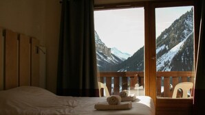 A hotel room with a bed, a view of snow-covered mountains through a balcony, and a wooden railing. - Wifi, swimming pool, sauna, tv, 45m², Pralognan-la-Vanoise (Pralognan-la-Vanoise)