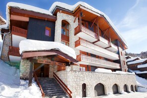 A multi-story building with stone and wood construction, featuring balconies and a staircase leading to the entrance. - Apartment for 4 People (La Plagne-Tarentaise)
