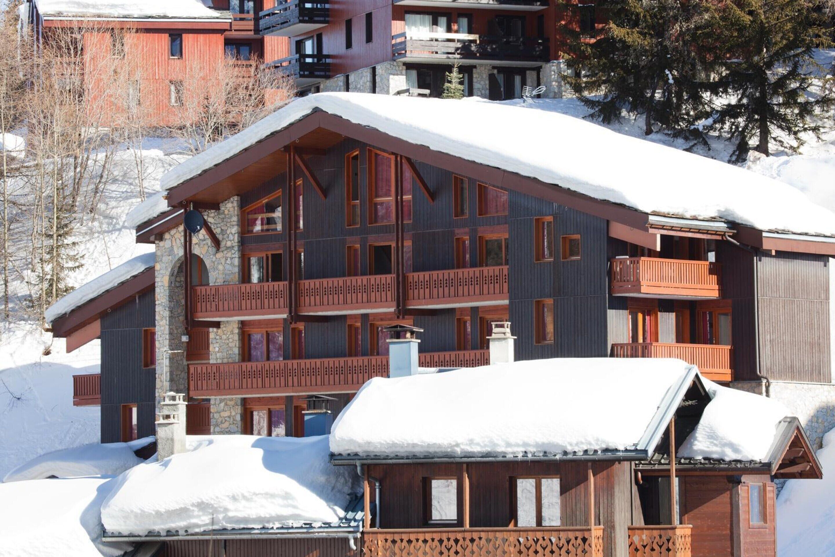 A multi-story wooden building with balconies, surrounded by snow.