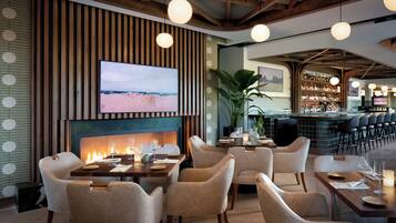 Un restaurante con chimenea, asientos y una zona de bar.
