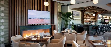 Un restaurant doté d’une cheminée, de tables et d’un bar.
