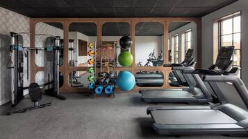 Un gimnasio con cintas de correr, pelotas de ejercicio y máquinas de pesas.
