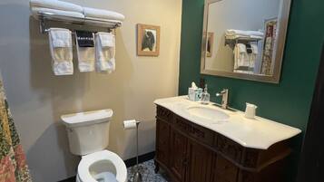 A bathroom with a toilet, sink, vanity, and towel rack.