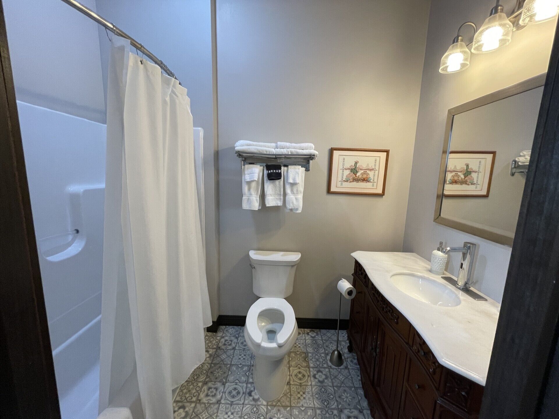 Baño con ducha, inodoro, lavabo y espejo.