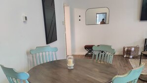 Un comedor con una mesa redonda de madera rodeada por cuatro sillas turquesas con asientos acolchados.
