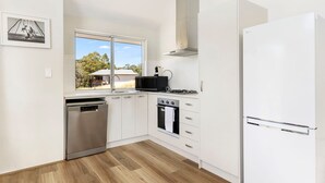 Une cuisine moderne avec des meubles blancs, un lave-vaisselle, une cuisinière et un four à micro-ondes.
