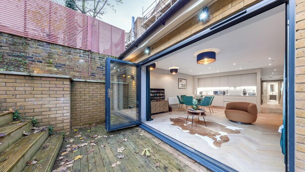 Un intérieur moderne avec une porte vitrée donnant sur un espace de vie comprenant un canapé, une table basse et une table à manger.