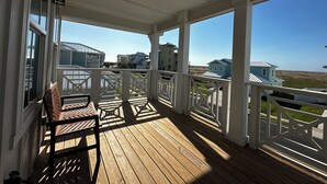 En træterrasse med hvide gelændere, der udover et boligområde med huse og en klar himmel.