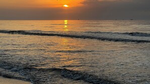 Solnedgang over et roligt hav, hvor bølgerne forsigtigt slår mod stranden.