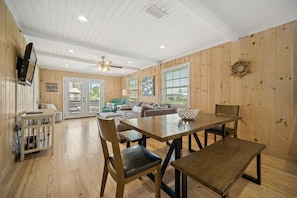 A spacious room with a wooden floor, a dining table with chairs, a sofa, and a ceiling fan. - Don t Worry Beach Happy 6 BR 4 BA Sleeps 20 (Gulf Shores)