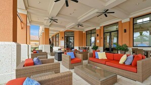 An outdoor lounge area with wicker furniture, red cushions, and ceiling fans. - Beautiful Townhome, Old Town (Kissimmee)