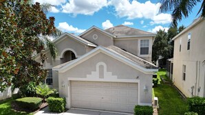 A residential house with a garage, a driveway, and a well-maintained lawn. - Stunning 6 bedroom vacation villa (Kissimmee)