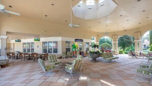 A spacious indoor area with multiple seating arrangements, including chairs and tables, and a ceiling fan. - Stunning 6 bedroom vacation villa (Kissimmee)