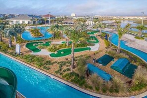 Une piscine, un parcours de golf et des palmiers.