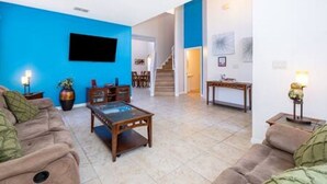Uma sala de estar com uma parede azul decorativa, uma mesa de centro de madeira e um sofá.