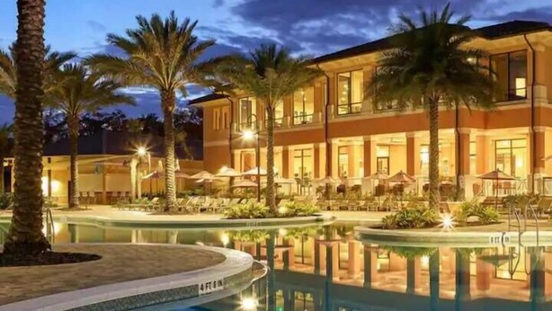 Ein Hotel mit Pool, Palmen und Sitzbereichen im Freien.