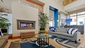 Eine moderne Lobby mit einer Couch, einem Glastisch, einem an der Wand montierten Fernseher und einem Empfangsbereich.