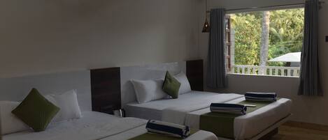 Een hotelkamer met twee bedden, een raam met uitzicht op groen, een airconditioning en een houten plafond.