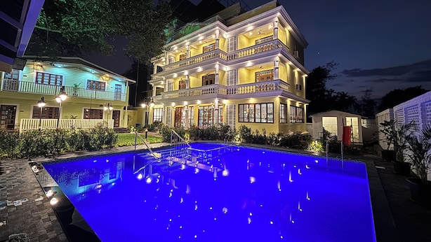 Un hotel de varios pisos con piscina por la noche.