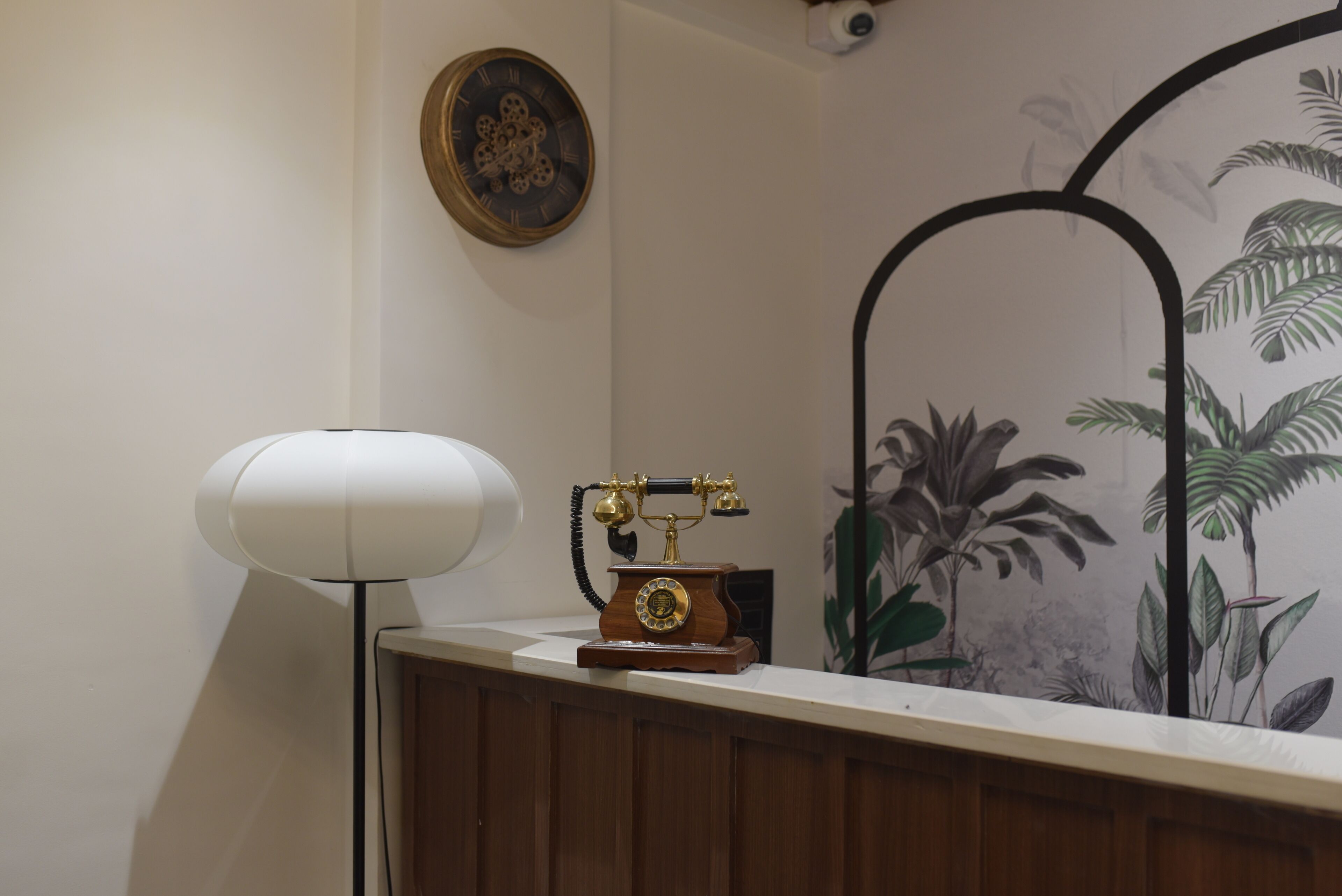 A wooden desk with a vintage telephone and a modern lamp.