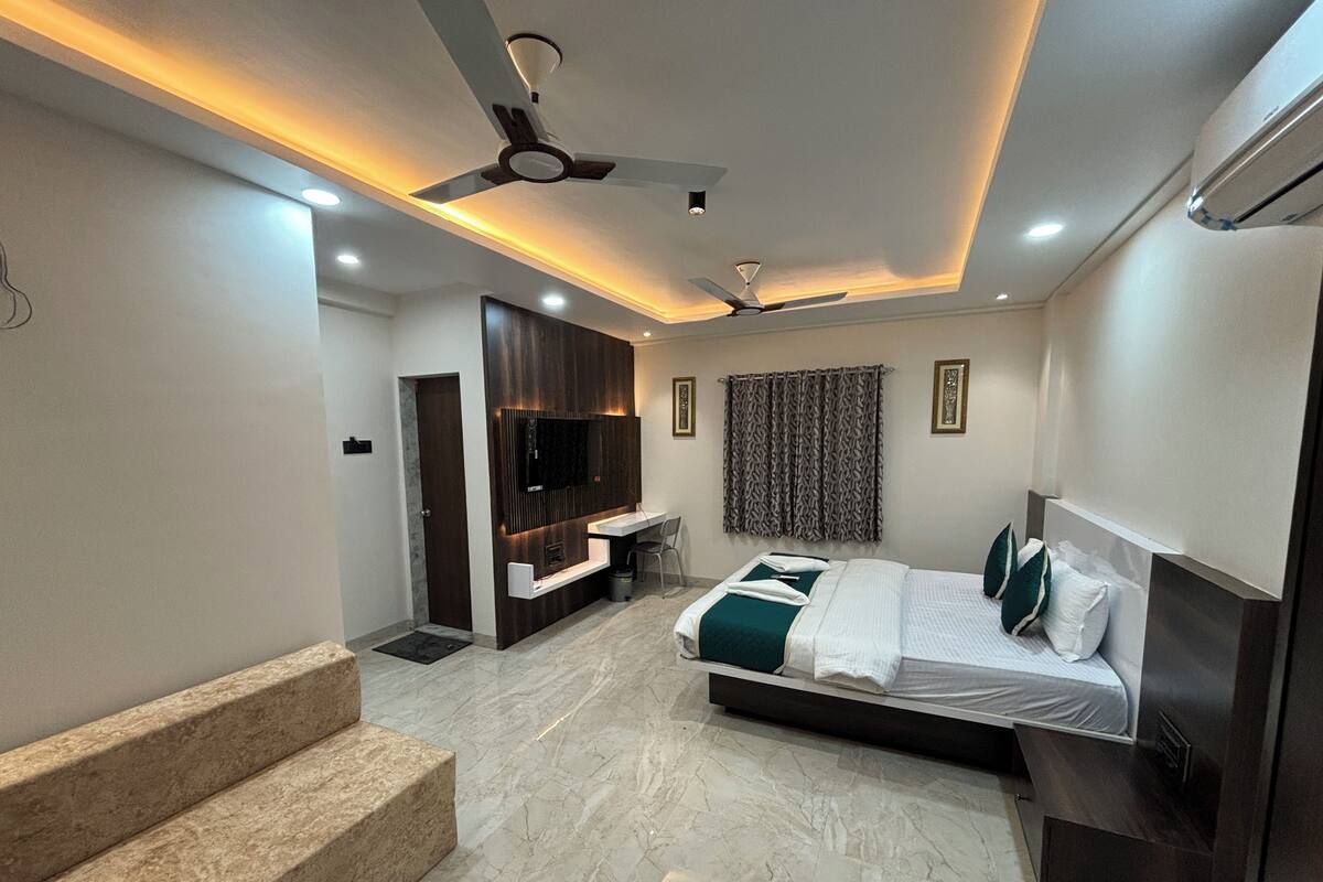 Ein modernes Hotelzimmer mit Bett, Schreibtisch, Fernseher, Deckenventilator und einer Treppe.