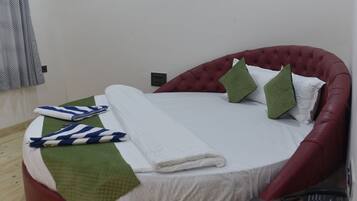 A neatly made bed with a red headboard, white bedding, and green and white pillows.