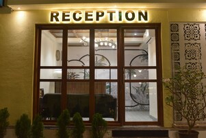 Una zona de recepción con un letrero sobre la entrada, una araña y una planta en maceta.