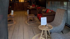A cozy, tent-like interior with a bar area, leather sofas, and a patterned armchair.
