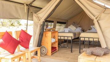 Una carpa con dos camas, una mesa de madera y un banco.