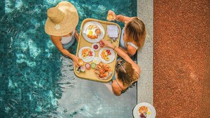 A top-down view of two people at a poolside table with a tray of food.