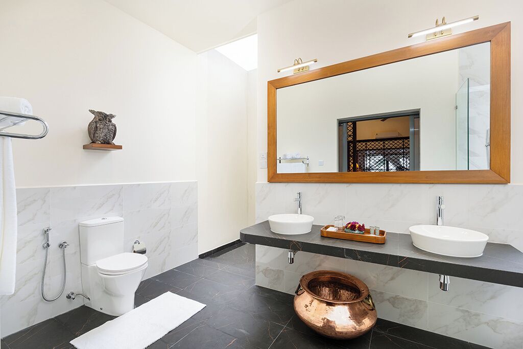 Un bagno moderno con due lavabi, un ampio specchio e un lavabo in rame.