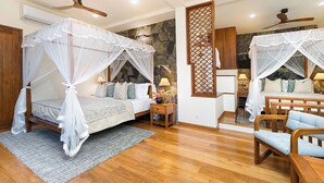 A bedroom with a bed under a canopy, a wooden nightstand, a chair, and a small table with a lamp.