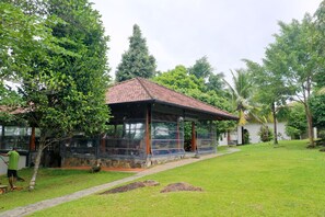 A covered outdoor seating area with a tiled roof, surrounded by lush greenery and a well-maintained lawn. - Heavensa Villas and Suites by The Clarks (Galle)