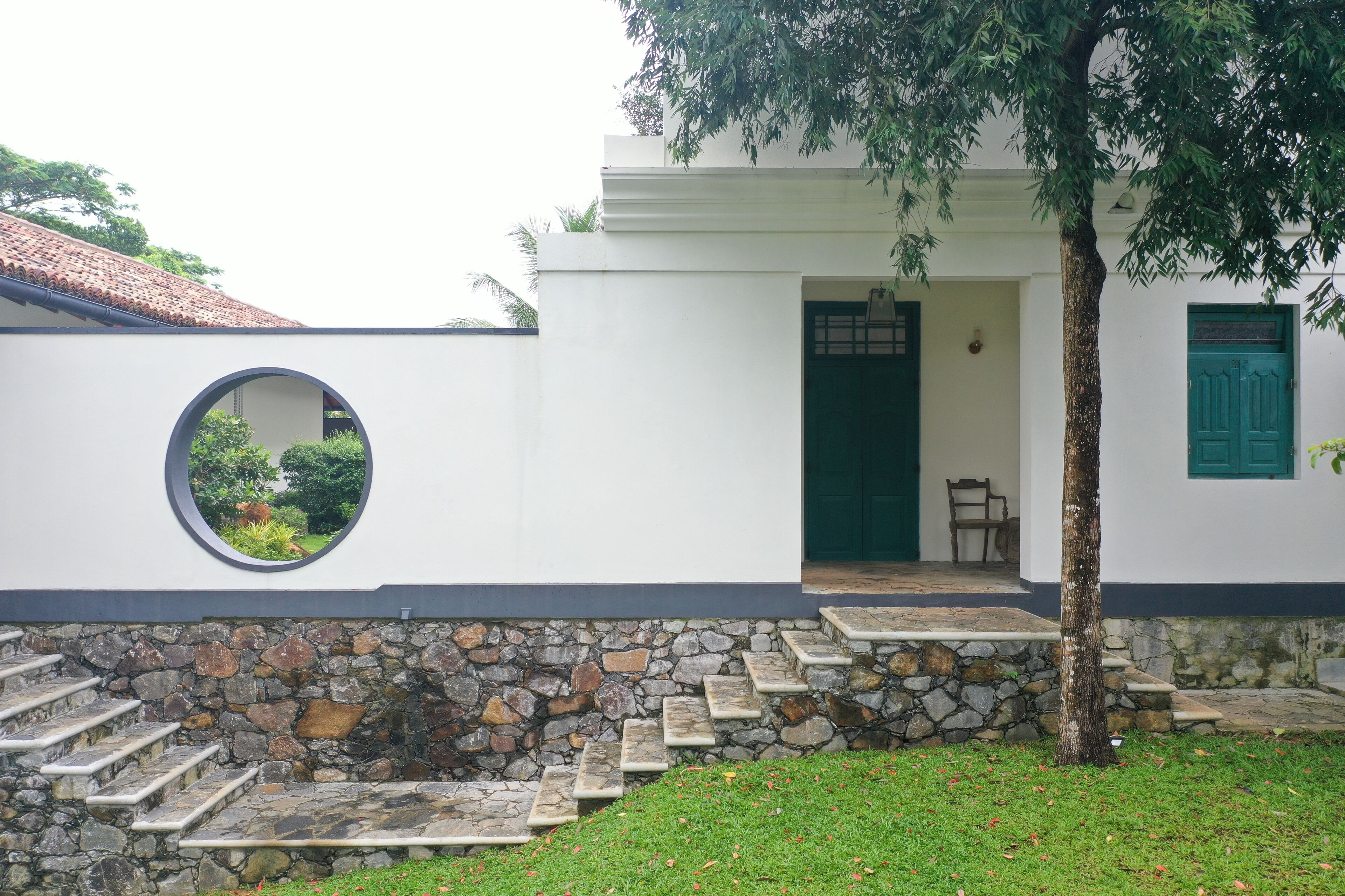 A building with a stone staircase, a round window, and a green door.
