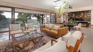 A modern living room with a glass coffee table, sofas, and a view of the outdoors.