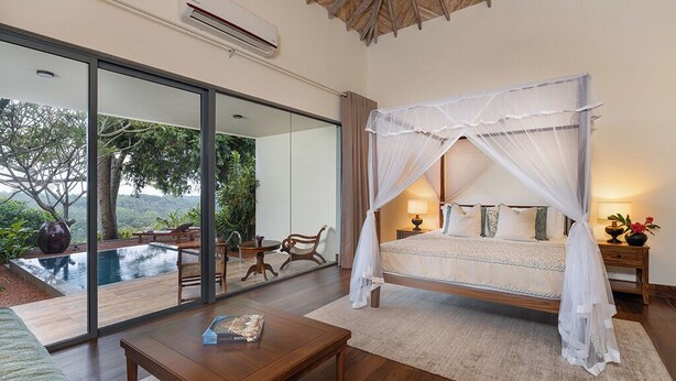 A bedroom with a canopy bed, a large window, and an outdoor pool view.
