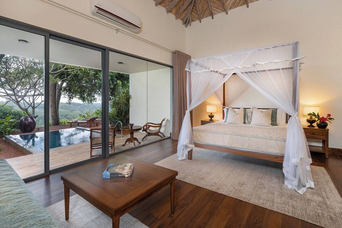 A bedroom with a canopy bed, a large window, and an outdoor pool view.