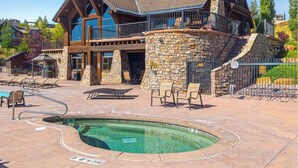 Un edificio grande de varios pisos con fachada de piedra y un área de piscina con sillones de descanso.