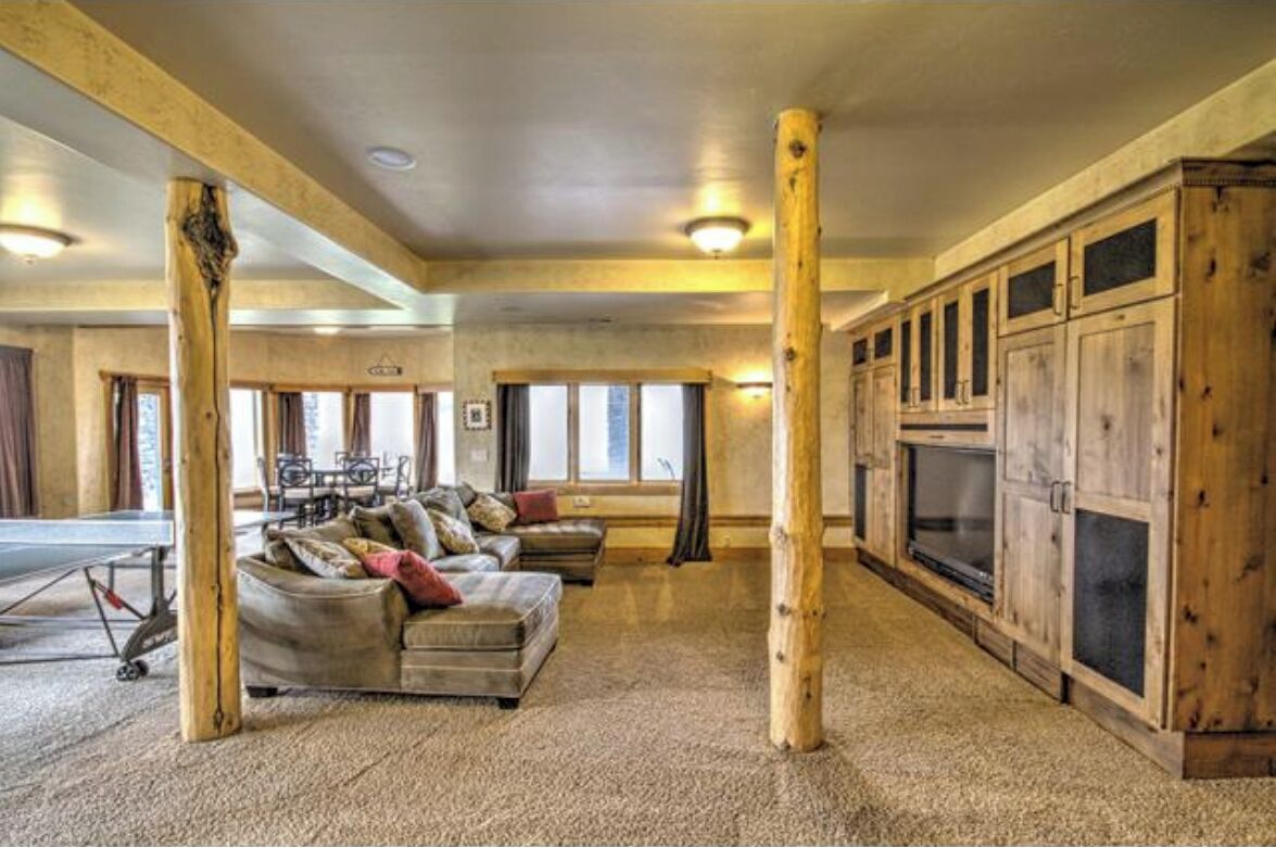 A spacious living area with a sofa set, wooden pillars, and a large cabinet.
