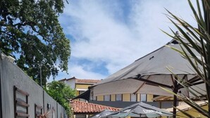 A swimming pool area with lounge chairs, umbrellas, and a tiled patio. - Recanto do Porto Hotel (Porto Seguro)