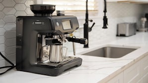 Una cocina moderna con cafetera espresso integrada, un lavamanos y un tostador.