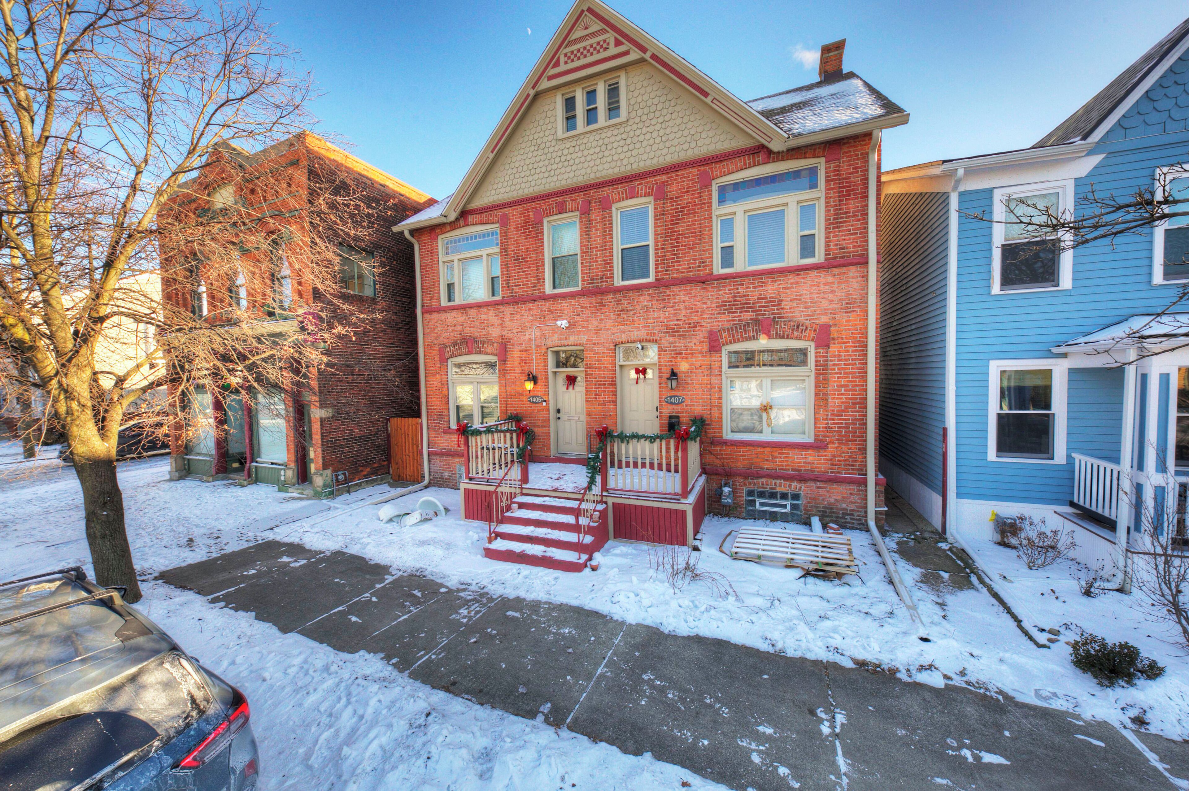 A red brick house with a front porch, a mailbox, and a number 1405 sign.