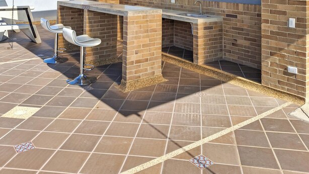 An outdoor patio with a glass enclosure, a brick barbecue area, and two bar stools. - Beautiful 5 star Loft - near Iserra 100 Bogota (Bogotá)