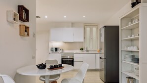 Eine moderne Küche mit weißen Schränken, einer zentralen Kochinsel mit Sitzgelegenheiten und einem eingebauten Backofen.